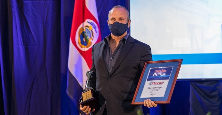 Masked man accepting a Costa Rican government award for MicroTechnologies on stage