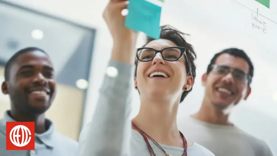 Smiling team placing sticky notes on a wall during a strategy session