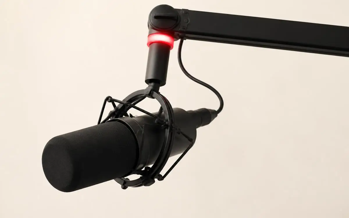 Studio microphone on a boom arm with a red recording light